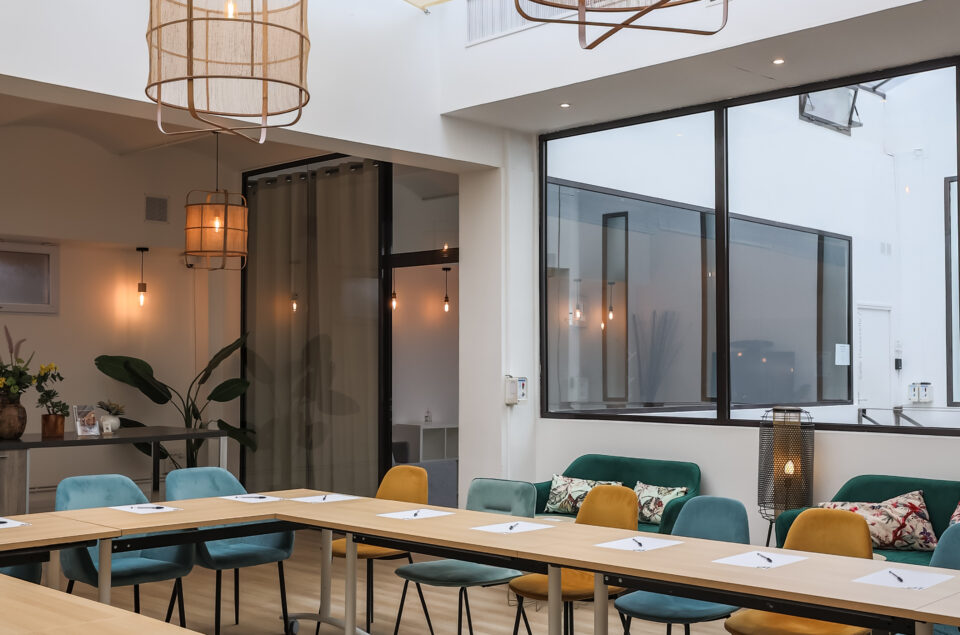 Loft Eiffel avec table en formation U. Feuilles et stylo sur chaque place. Lustre au plafond