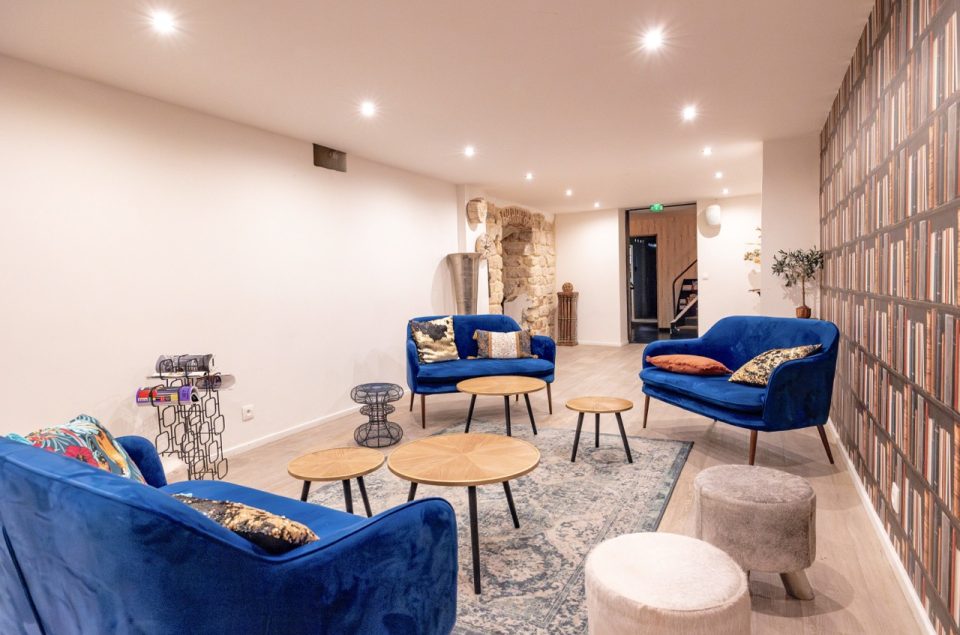 Salle Les Chais avec table basse en bois et canapé en velours bleu