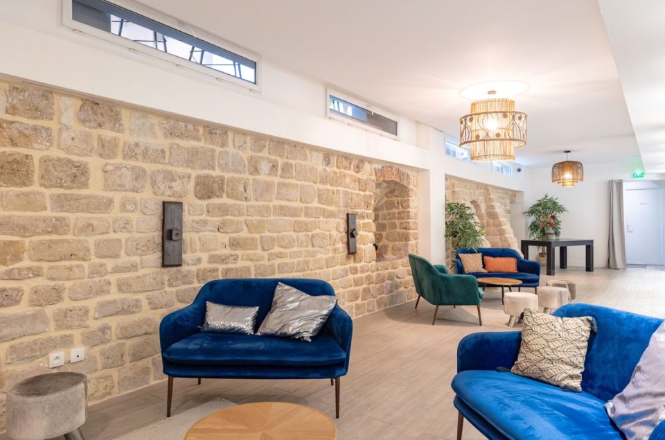 Salle Les Chais avec table basse en bois et canapé en velours bleu