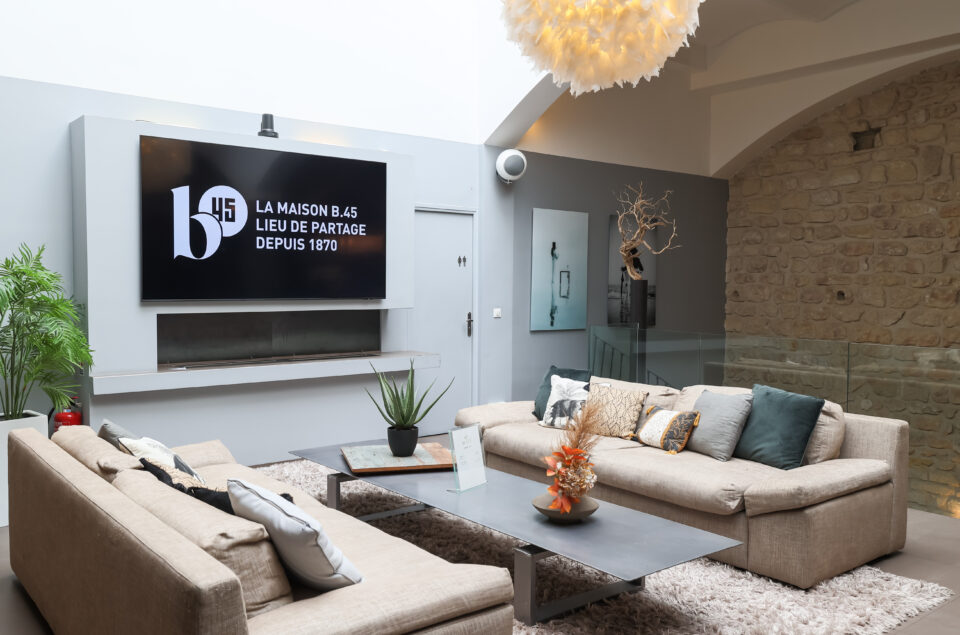 Télévisons du Grand Loft avec canapé en tissu beige devant.