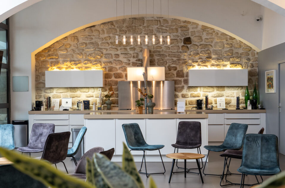 Cuisine et plan du travail du grand loft devant un mur en pierre. Chaise et table basses devant