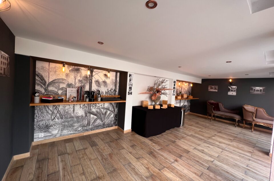 Vue de l'espace couvert de la cour, avec des tables et des mets posés dessus. Canapé style baroque marron