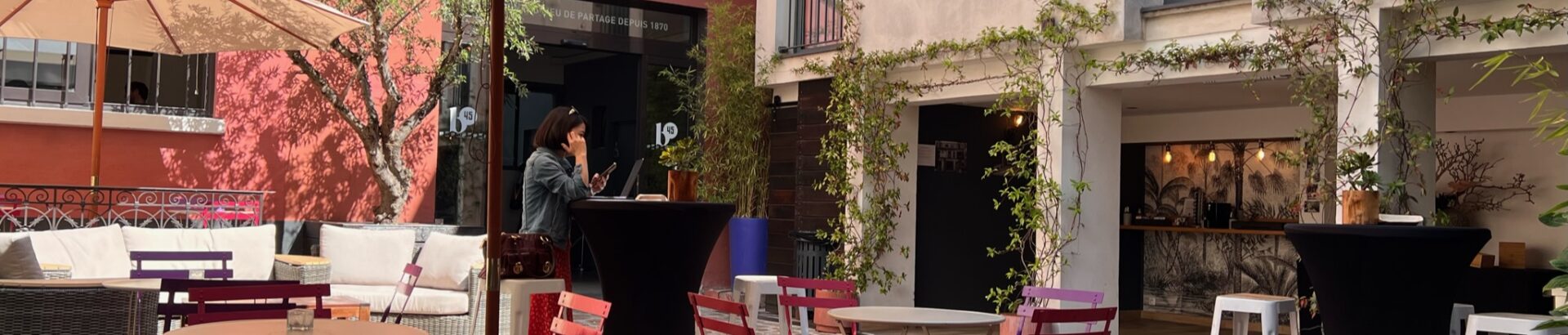 Vue entière de la Cour avec des chaises colorées violettes et roses, des parasols mais aussi des canapés
