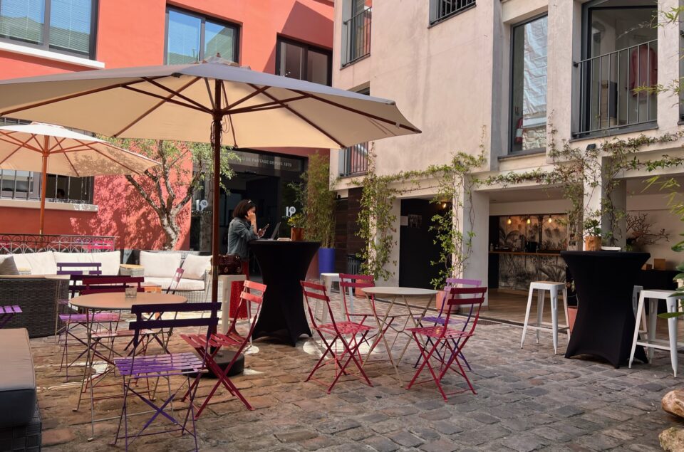 Vue entière de la Cour avec des chaises colorées violettes et roses, des parasols mais aussi des canapés