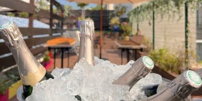 Premier plan seau de champagne rempli de glaçon sur le rooftop et seconde plan parasol et table