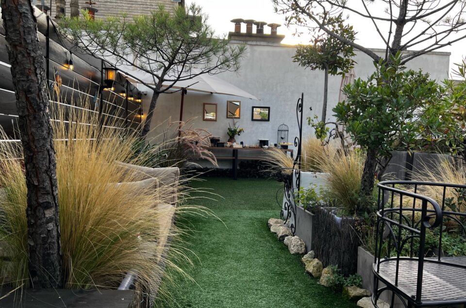 Allée du rooftop et verdure sur les cotés. Au fond un buffet avec des mets