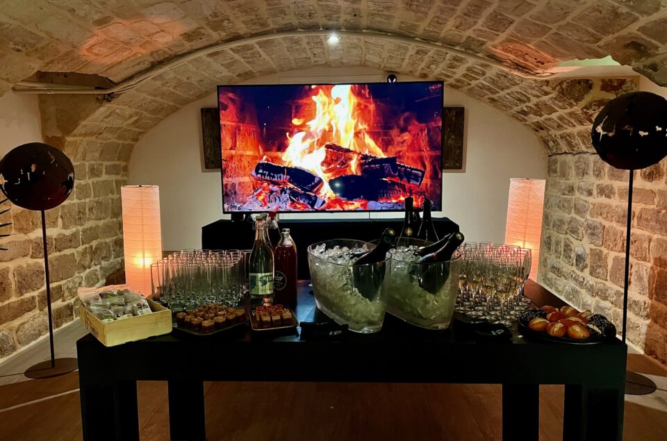 Bar à cocktail dans les Chais avec petites bouchées et feu de cheminées sur la télé du fond