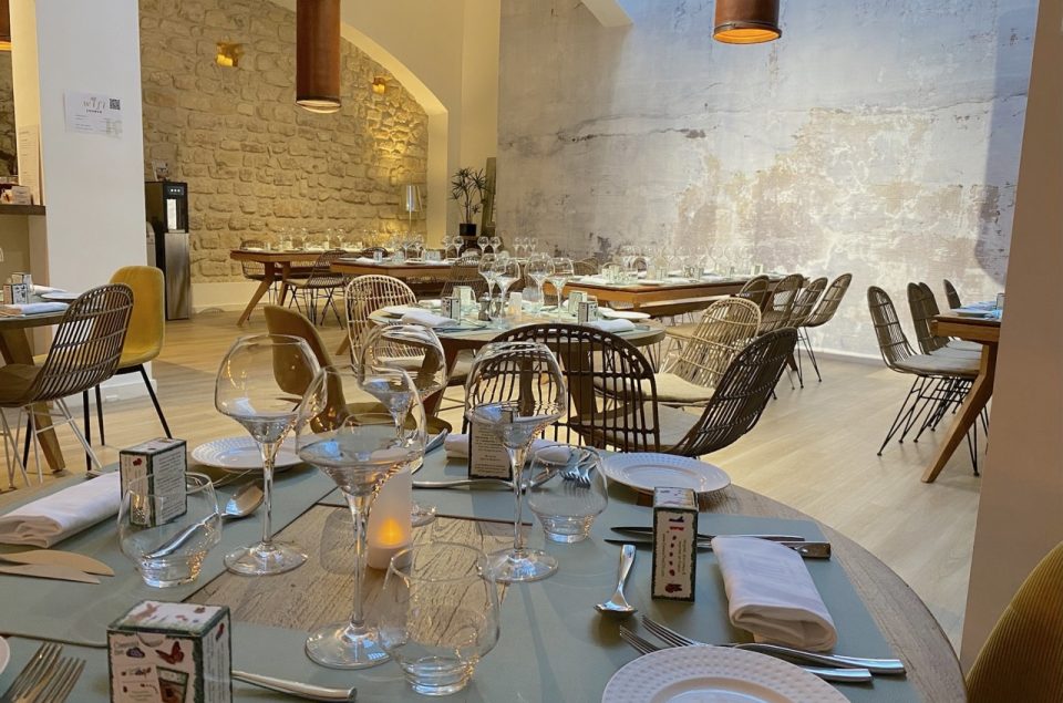 Mise en place pour un repas dans la salle Louage avec vue sur la table et la mise en place de couvert, assiette et verre